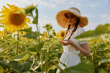 woman with pigtails in a straw hat in a white dress a field of sunflowers agriculture unaltered