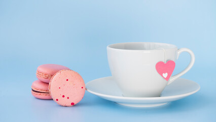 White cup with tea and pink macarons