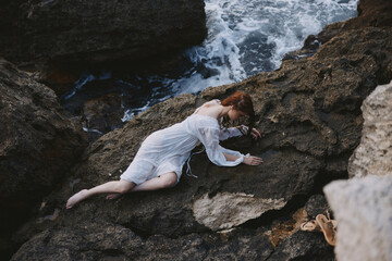 woman lying on her back on a rocky seashore view from above