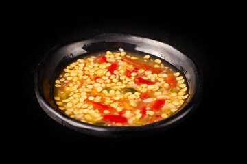 Close up of  Seafood Dipping Sauce in a black small bowl isolated on black background, The dipping sauce is popular with seafood, has a spicy and sour taste.