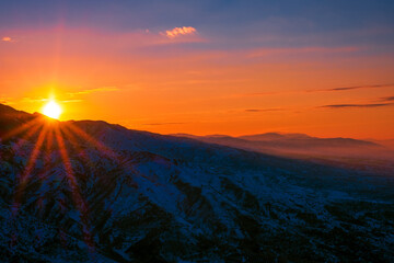 Magical atmosphere of a sunset in the highlands; sunset sky over snow-capped mountain ridges