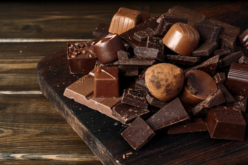 Chocolate pieces and candy on dark wooden table.