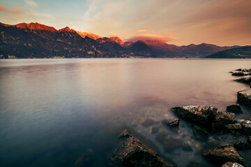 sunset over the lake iseo in italy with pink clouds over the mountains