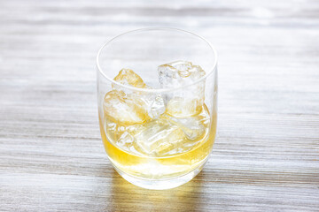 glass with single malt scotch whisky on the rocks on gray wooden table