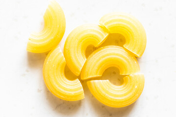 several uncooked chifferini rigati pasta pieces on gray plate close up