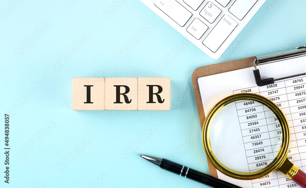 Poster irr word on wooden cubes on a blue background with chart and keyboard