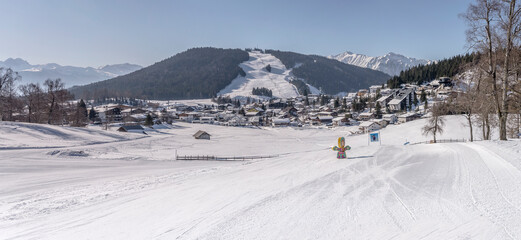 Gschwankopf ski runs loom out over touristic village snowy roofs, Seefeld, Austria