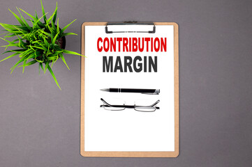 CONTRIBUTION MARGIN on the brown clipboard on the grey background. Business concept