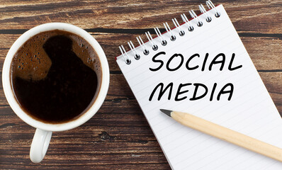 SOCIAL MEDIA text on notebook with coffee on the wooden background