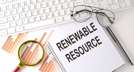 RENEWABLE RESOURCE text written on a notebook with keyboard, chart,and glasses