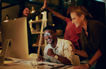 Pushing through the night really paid off. Shot of a group of businesspeople looking at something on a computer in an office at night.