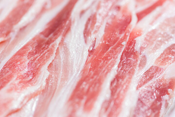 Close up top view pack bacon, pieces raw meat of fresh red pork with white fat slices are sliced into thin strips stacked on top of each other
