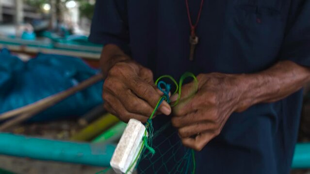 close up of black asiatic skilled hands dis entanglement fisherman net on tropical beach, bali island Indonesia