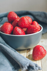 Fresh sweet strawberry on a blue plate and linen towel. Big ripe berries for a healthy meal in summer on wooden table
