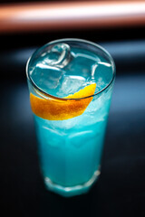Glass of sweet cool blue cocktail with lemon and ice