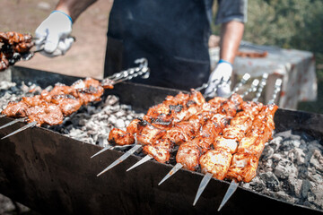 View of the hands of a shish kebab man who fries shish kebab on the grill outdoor