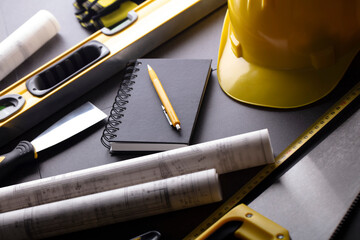 Business contraction theme. Tool kit of the contractor: yellow hardhat, libella, hand saw. Plans...
