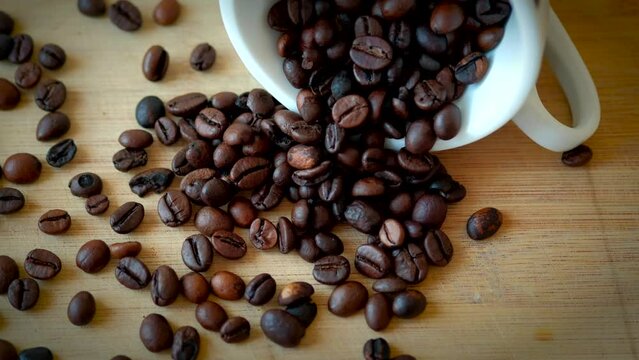 Top view of coffee cup filled with coffee beans on wooden table. Selective focus.