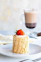 Strawberry log cake on a white background. With hot chocolate on the side. close up