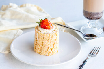 Strawberry log cake on a white background. With hot chocolate on the side. close up