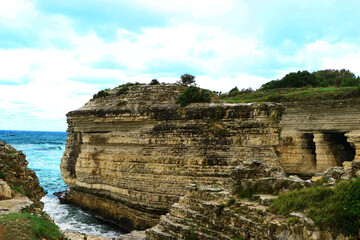 Waves reach to coastline that surrounded with rocks.