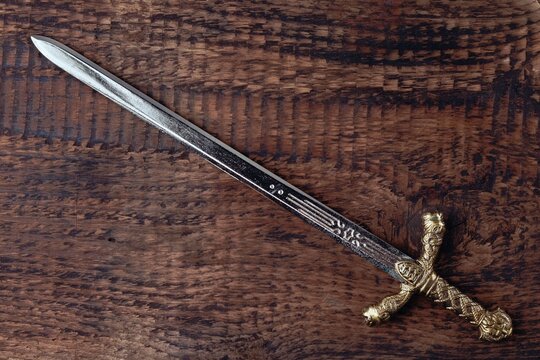 Antique knight's sword on the background of gray wood texture. Religion and culture