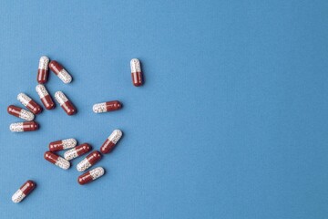 Colored capsules with medical drugs on a blue background. Copy space, flat lay