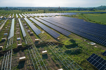 Aerial view of big electric power plant under construction with many rows of solar panels on metal frame for producing clean electrical energy. Development of renewable electricity sources © bilanol