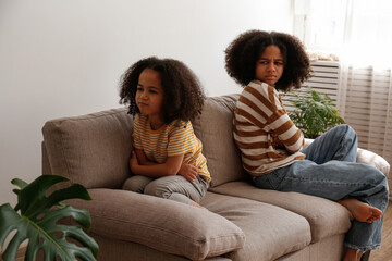 Younger and older sister in a state of emotional stress displeased with each other. Two black girls of different age arguing. Black female siblings having a fight. Background, copy space, close up.