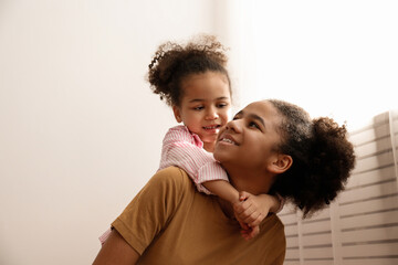 Younger and older sister spending time together at home. Two black girls of different age playing at home. Black female siblings having fun and bonding. Background, copy space, close up.
