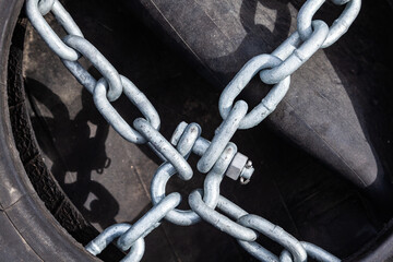 Old tires and rubber with chains and bindings for sea vessels and tugs, piled up, close-up.