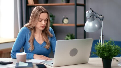 Confident business woman working studying remotely use laptop paper notes reminders at workplace