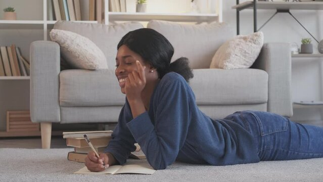 Creative writer. Diary leisure. Education lifestyle. Thoughtful dreamy inspired young woman writing notes in journal on floor at home living room.