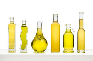 Variety of olive oils in bottles on white shelf, isolated on white background