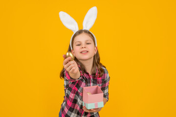 easter child in bunny ears hold box and egg on yellow background