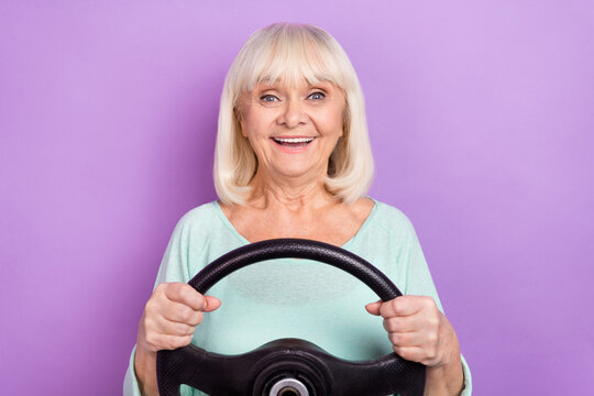 Photo of cheerful positive retired old lady hold steering wheel wear teal shirt isolated violet color background