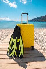 Suitcase with flippers on the seashore