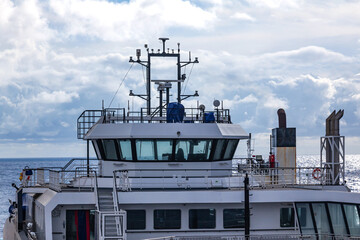 The upper part of the ship with the bridge, navigation lights and radars, view from the outside to the sea.