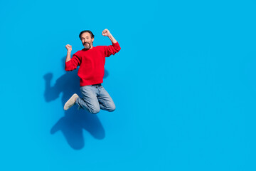 Fototapeta na wymiar Full size photo of funky rejoiced male jumping raise fists in victory celebrate fan support isolated on blue color background