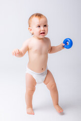 cute baby girl in a diaper stands in full height isolated on a white background