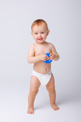 cute baby girl in a diaper stands in full height isolated on a white background
