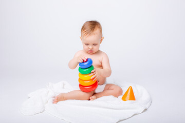 Fototapeta na wymiar Cute baby girl playing with colorful rainbow toy pyramid sitting on white background.Toys for little kids. Child with educational toy. Early development. a white background