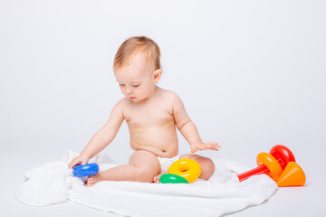 Cute baby girl playing with colorful rainbow toy pyramid sitting on white background.Toys for little kids.  Child with educational toy. Early development. a white background