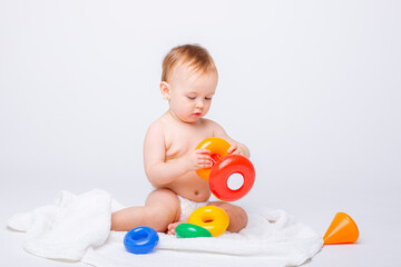 Cute baby girl playing with colorful rainbow toy pyramid sitting on white background.Toys for little kids.  Child with educational toy. Early development. a white background