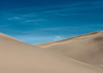 Fototapeta na wymiar Desert landscape. Sand dunes under the blue sky. Traces of wind on the surface of the sand dune.