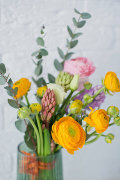 Beautiful bouquet with orange and pink ranunculus flowers, eucalyptus and hyacinth in a green vase