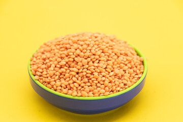 Red lentils pile isolated on yellow background, also known as Dry orange lentil grains, masoor dhal,