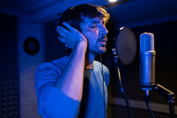 vocalist of a music band with microphone recording a song in a studio, Close-up of a male singer...