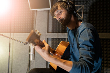 man recording a song with guitar in studio