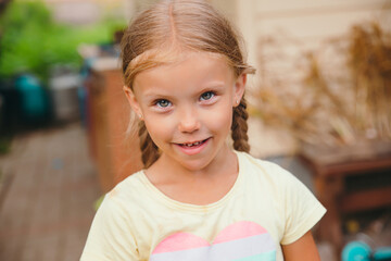 Close-up portrait of funny little girl with pigtails outdoor. Summertime